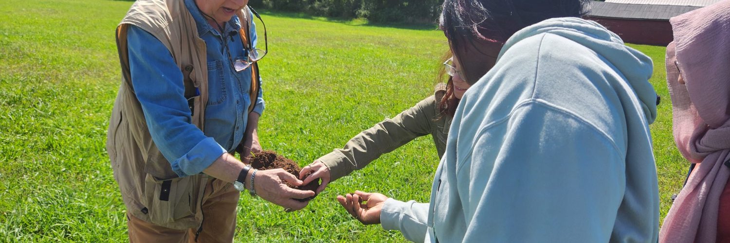 a group of people reaching to a shovel and touching segment of soil