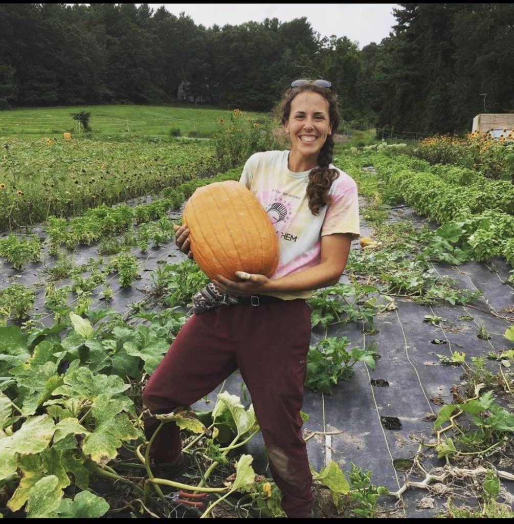 Nicole Davidow in a field holding a pumpkin