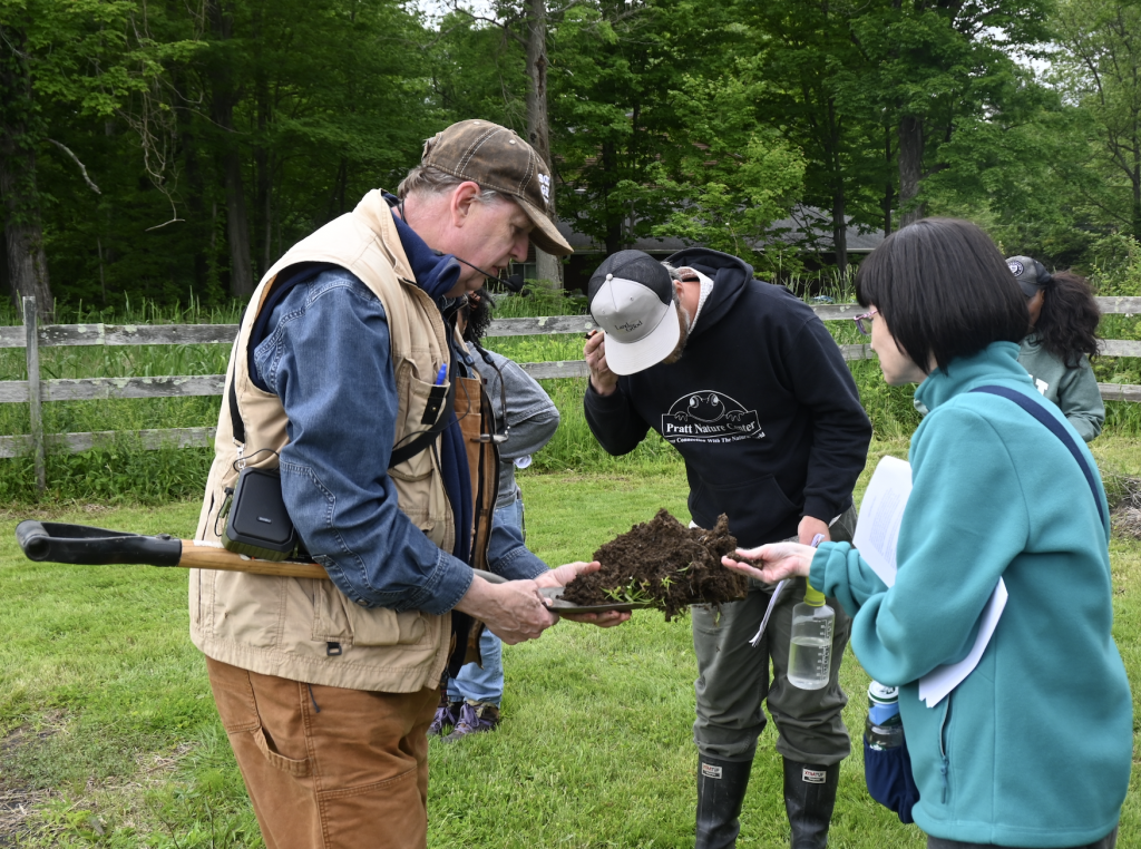 Kip holding a soil sample out for participants to touch and investigate