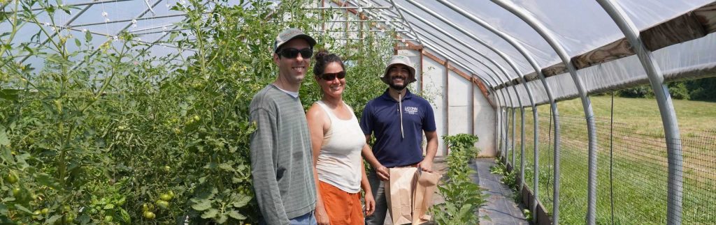 Three people standing in a greenhouse.